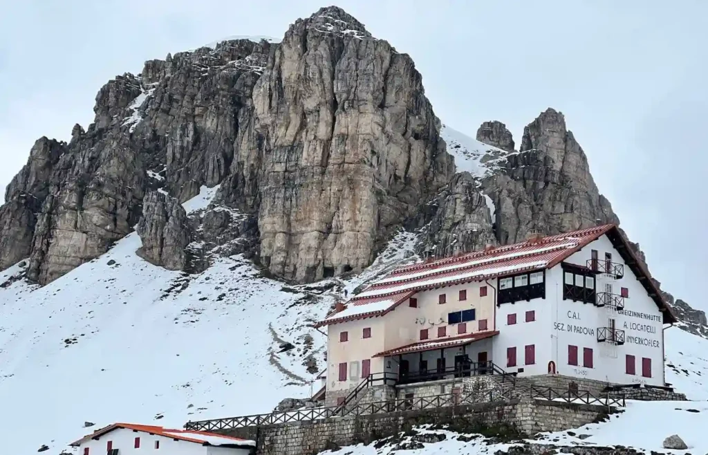 Refugio Locatelli nevado frente a montañas rocosas en Dolomitas.