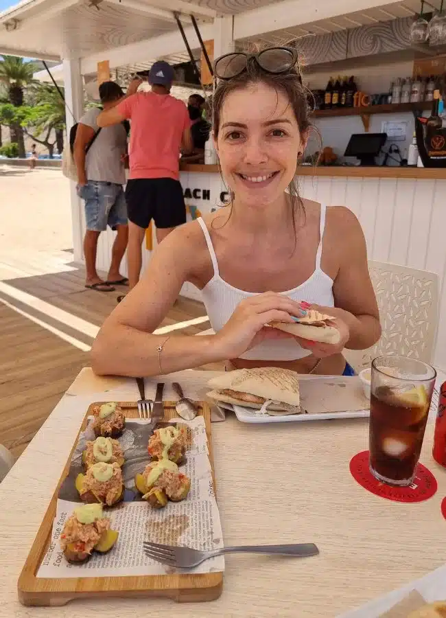 Mujer almorzando en un chiringuito de playa en Tenerife con vistas al mar.