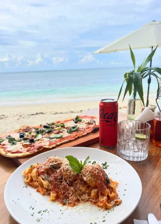 Plato de comida italiana con pizza y pasta en un restaurante frente a la playa en las islas Gili.
