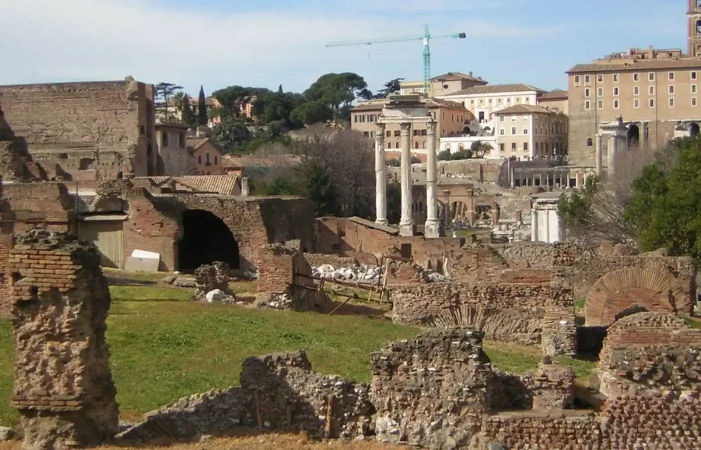 Ruinas del Foro Romano con edificios modernos y grúa.