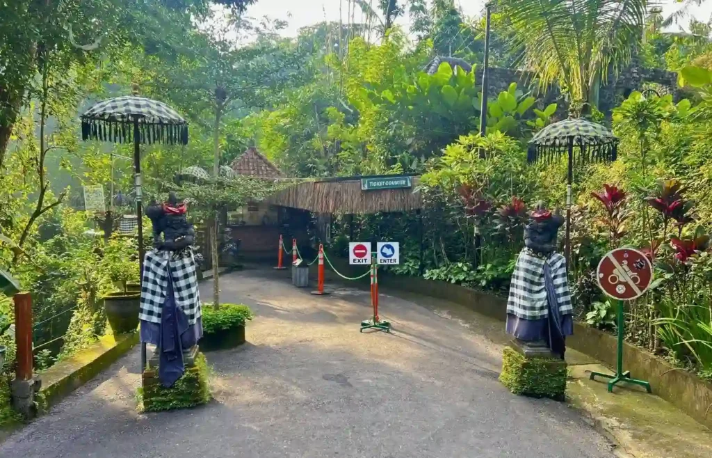 Entrada tropical con estatuas balinesas, taquilla y exuberante vegetación.