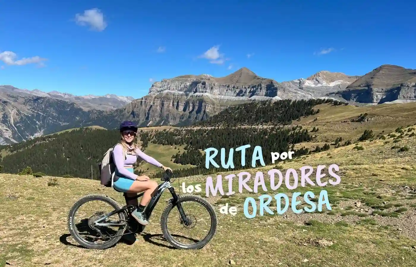 Ciclista saludando sobre su bicicleta eléctrica en un tramo despejado de la pista de las Cutas en Ordesa.