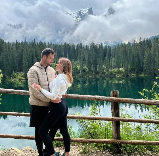 Pareja frente a un lago cristalino durante una ruta de senderismo.