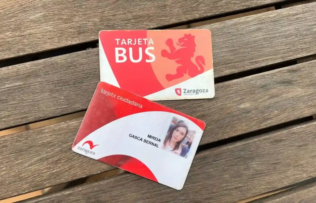 Dos tarjetas de Zaragoza: bus y ciudadana, sobre superficie de madera.