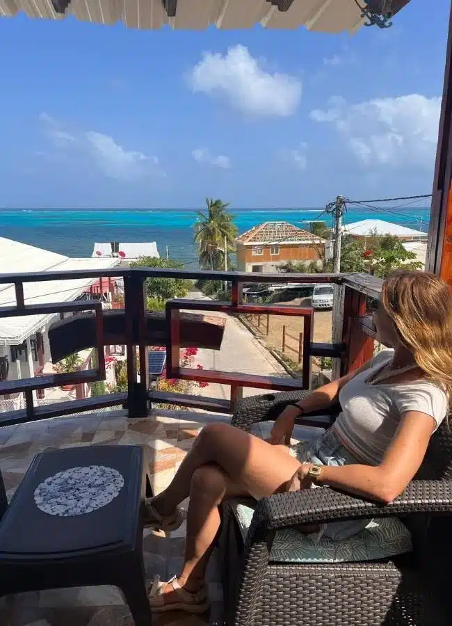 Mujer relajada en una terraza con vistas directas al mar caribeño.