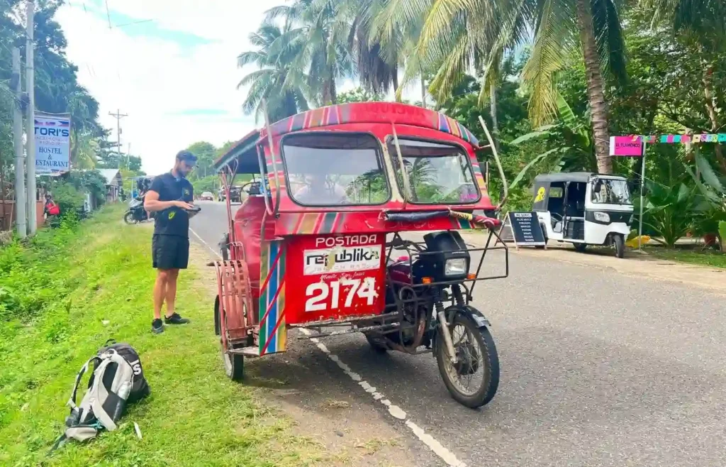 Triciclo rojo y motos aparcados en una calle típica de Filipinas.