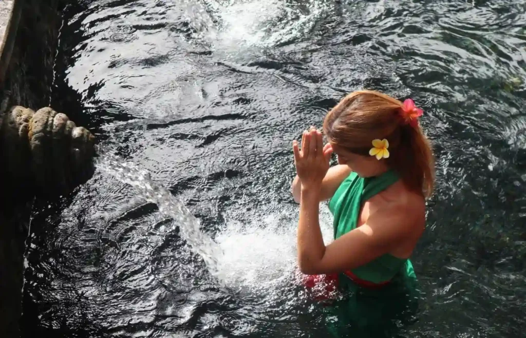 Mujer realizando el ritual de agua sagrada en las fuentes de Tirta Empul, Bali.