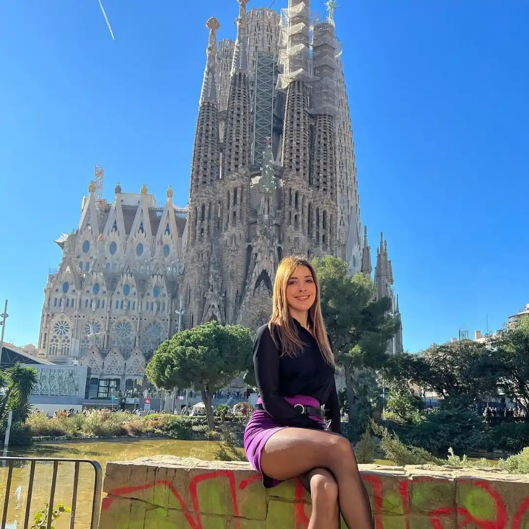 Mujer joven posando frente a la Basílica de la Sagrada Familia de Gaudí en Barcelona, España.