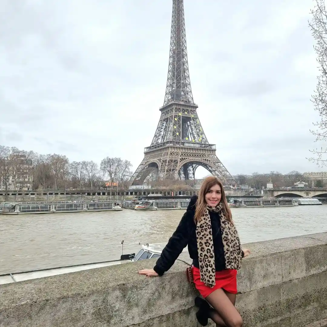 Turista caminando junto al río Sena con la Torre Eiffel de fondo en un día nublado en París, Francia.