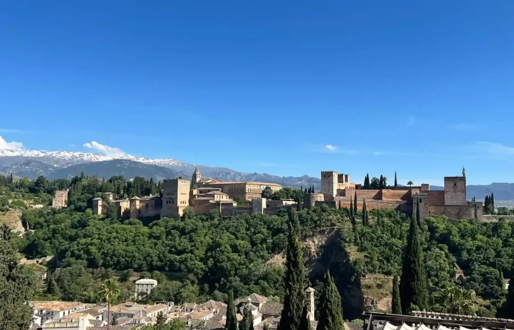 Panorámica icónica de la Alhambra, el Palacio del Generalife y las cumbres nevadas de Sierra Nevada desde el Mirador de San Nicolás en el Albaicín.