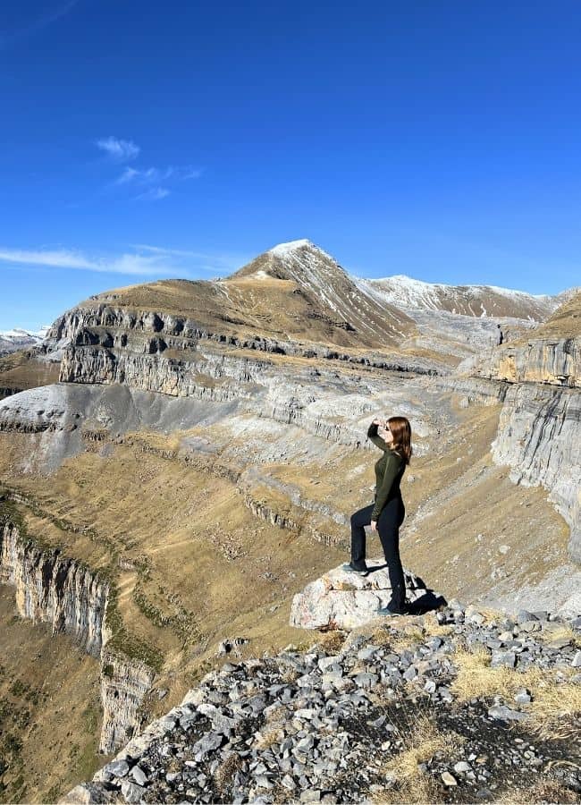 Una mujer de pie junto al precipicio de la Faja de las Flores admirando la inmensidad del cañón.