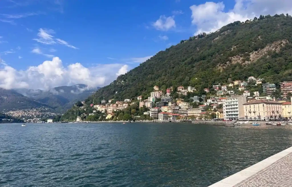 Paisaje del Lago de Como, montañas y casas bajo cielo azul.
